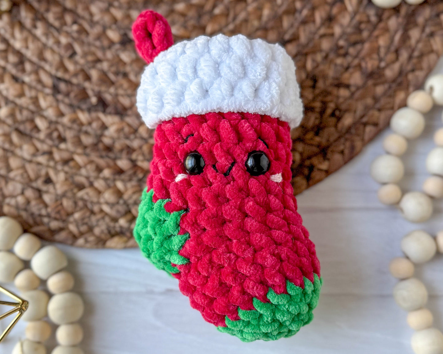 Crocheted Christmas stocking ornament with a white top and red body on a wooden surface.