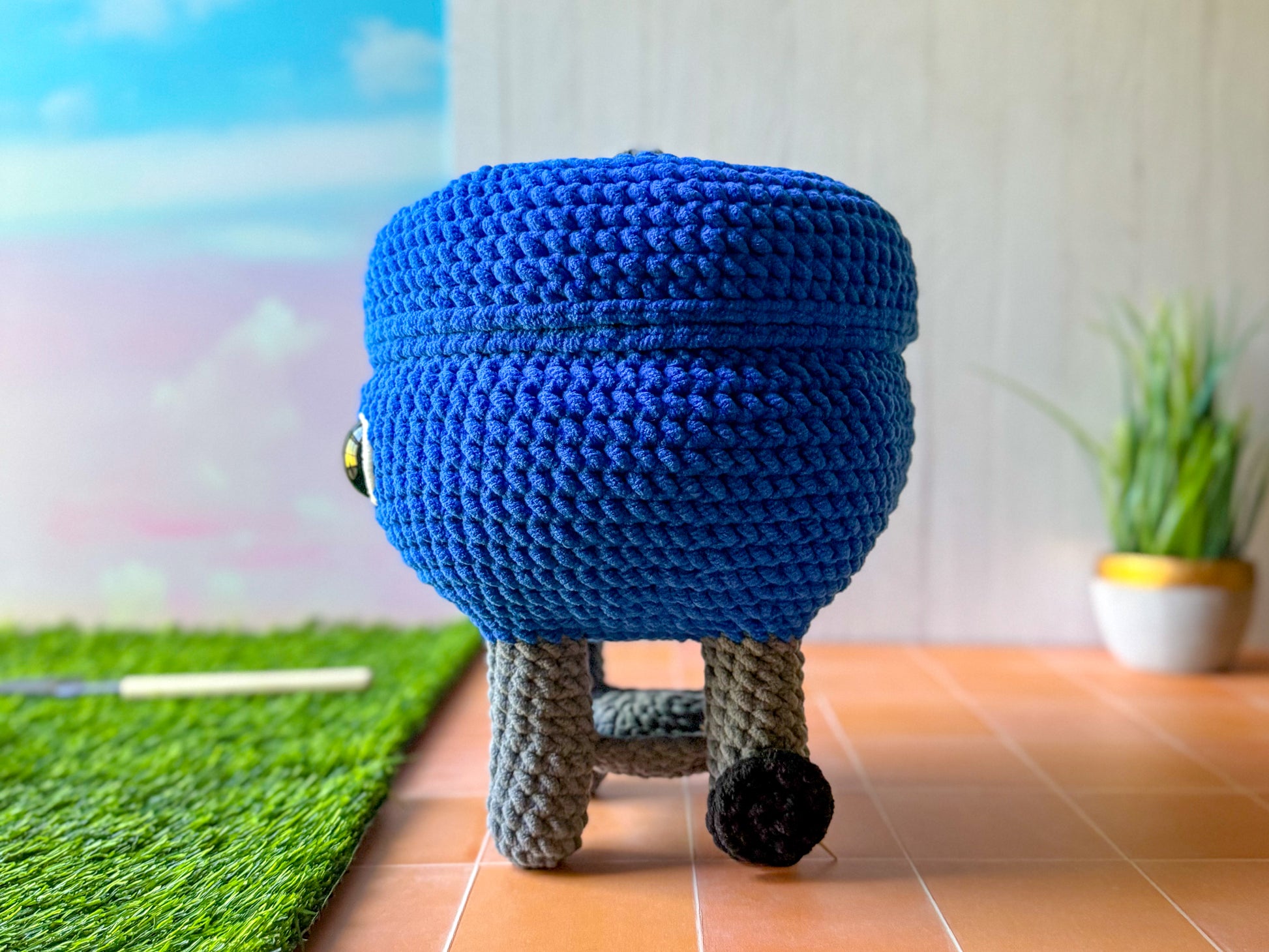 Side view of the Big BBQ Grill crochet plush, showing its round shape and wheel detail.
