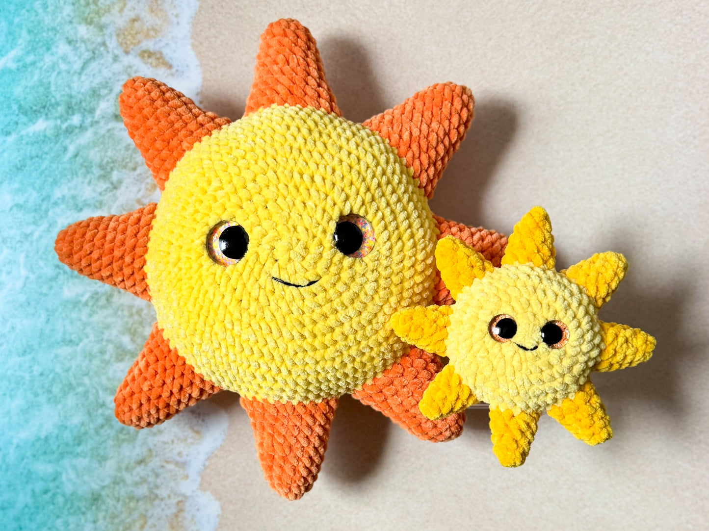 Two crocheted sun toys with faces on a textured surface.