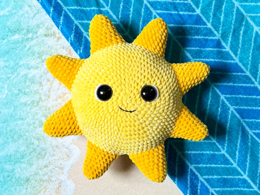Yellow sun-shaped plush toy with black eyes on a blue and white textured background