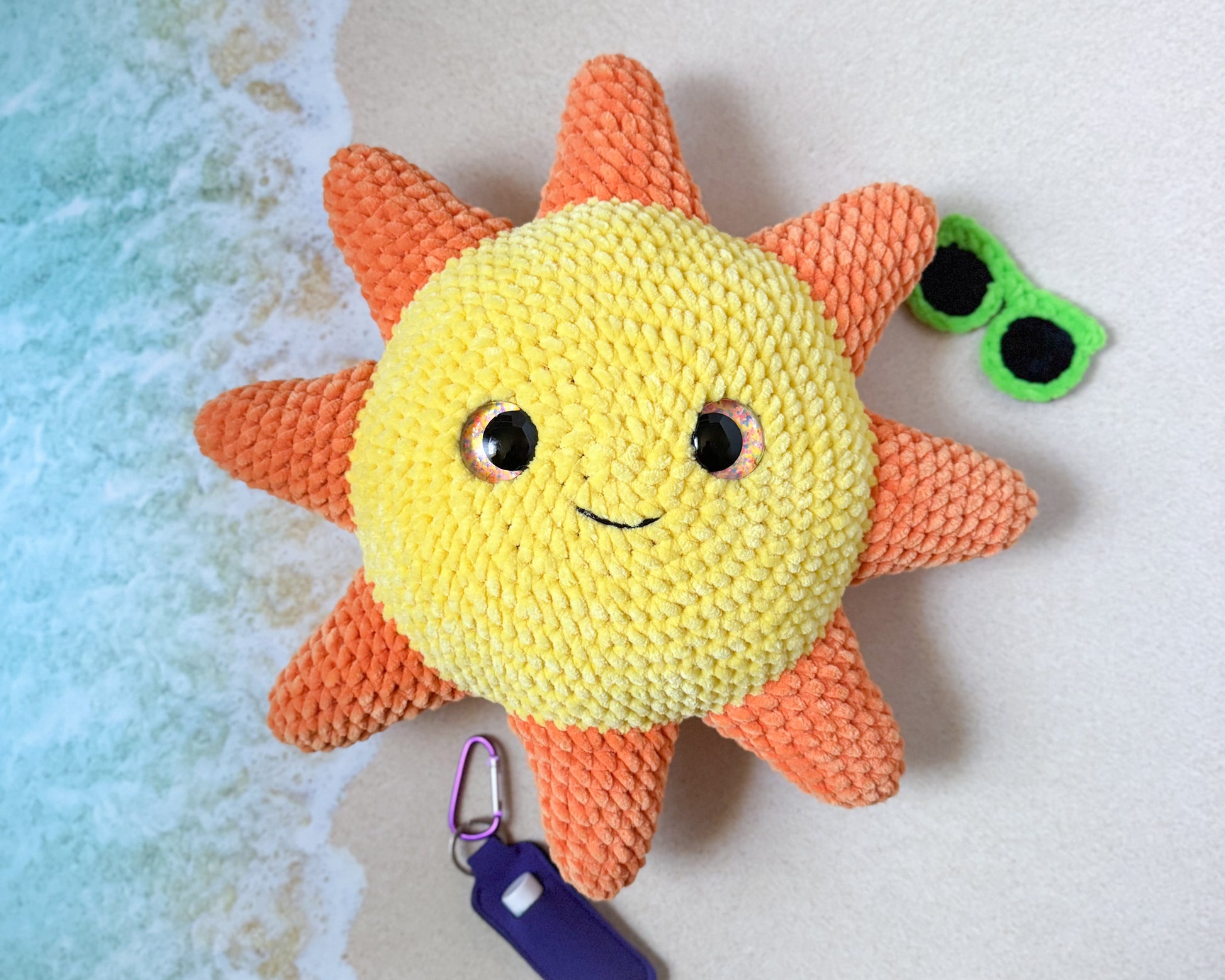 Crocheted sun-shaped toy with a keychain on a textured surface
