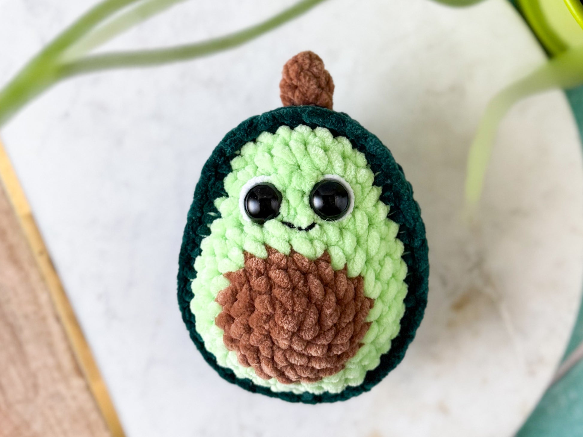 Crocheted avocado with a smiling face on a light background